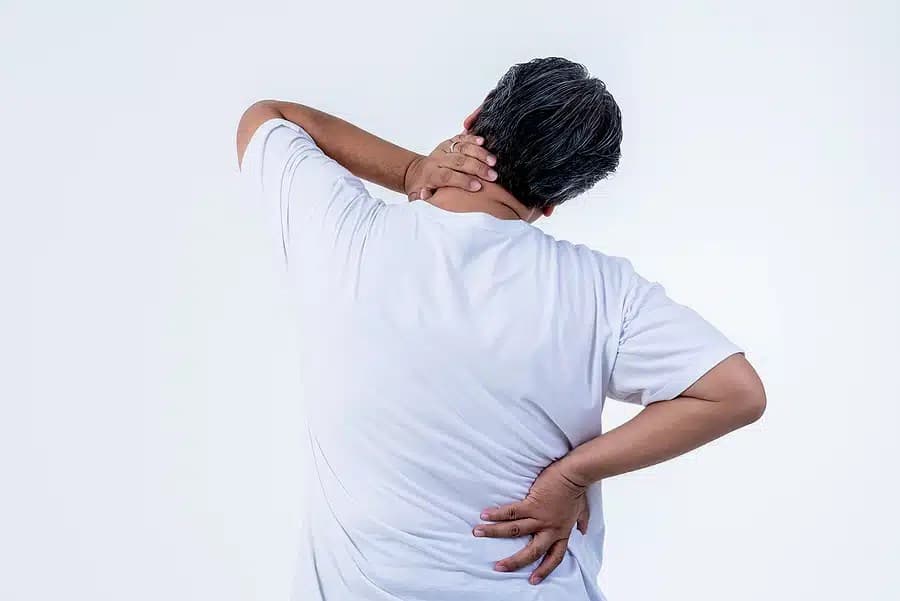 Older man seen from behind holding his neck and lower back