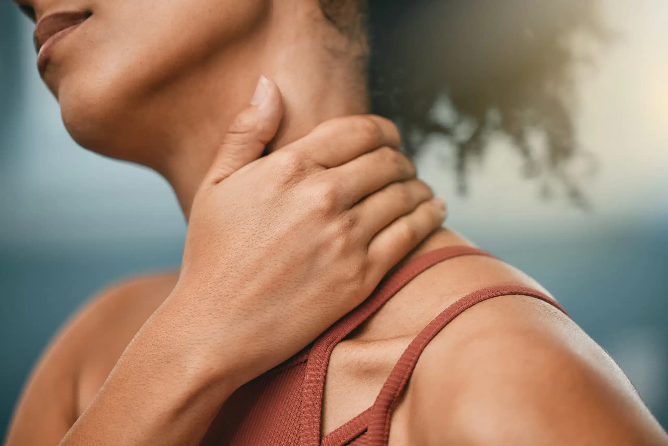 Close-up of a woman's hand resting on the side of her neck and shoulder