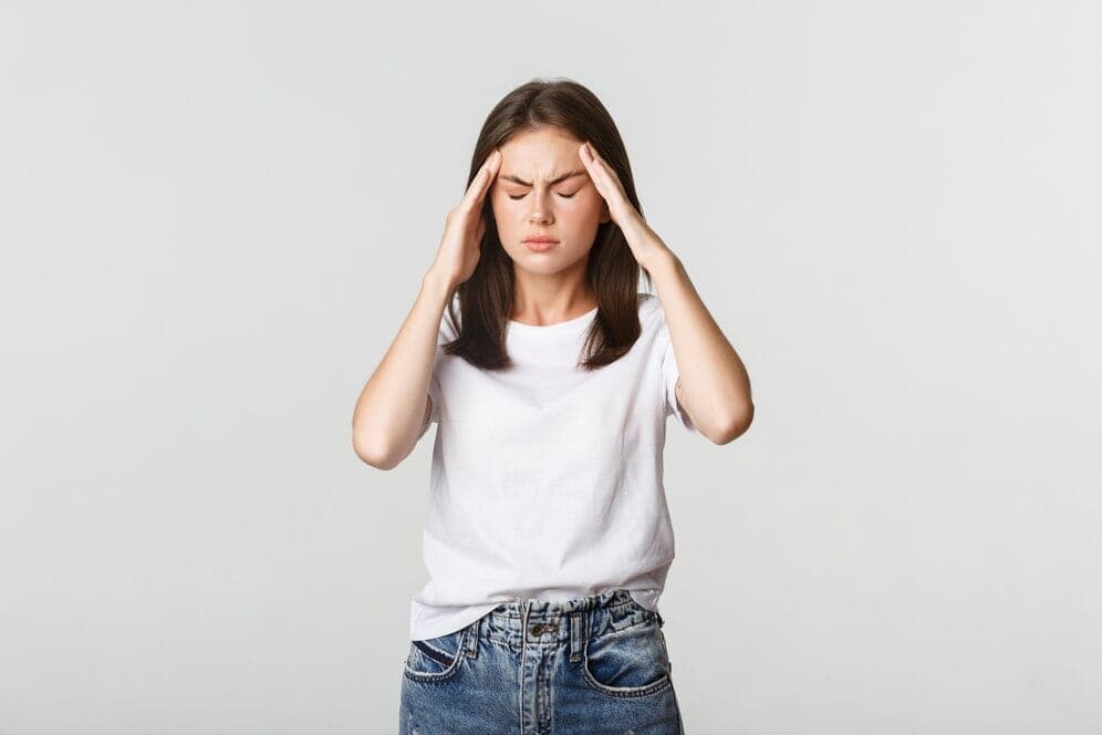 Woman with her eyes closed pressing her temples during a migraine
