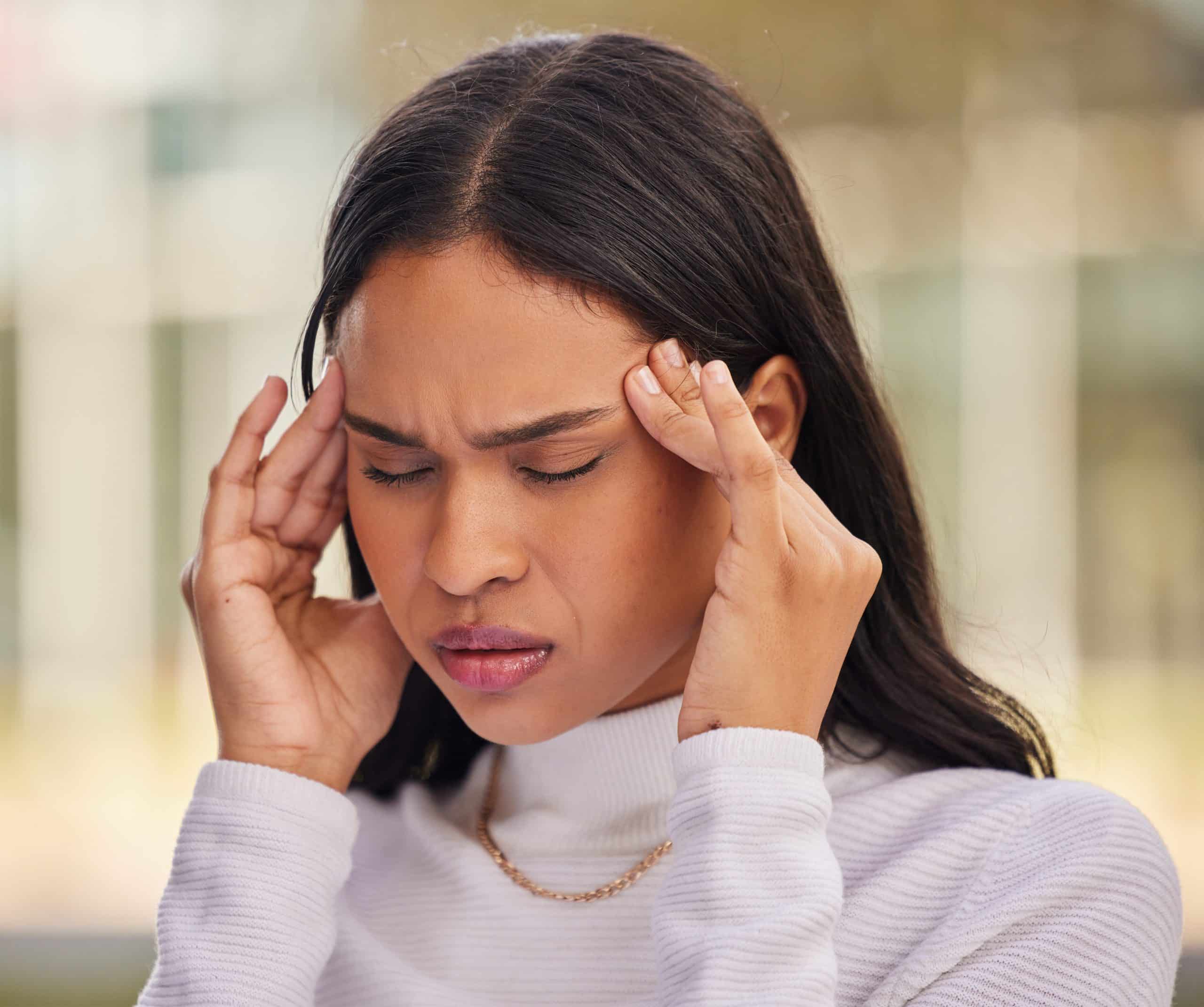 Woman pressing her fingertips to her temples with a headache